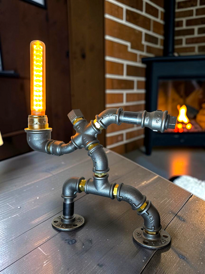 KerleKiste Hampelmann Tischleuchte aus dunklen Industrierohren mit leuchtender Edison-Glühbirne im Wohnzimmer