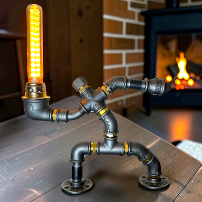 KerleKiste Hampelmann Tischlampe aus schwarzem Industrierohr mit Edison-Glühbirne vor einem Kamin